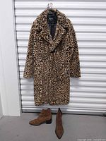 Full view of leopard print coat on hanger with boots below