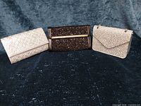 Front view of three glitter clutches: black center, champagne left and right