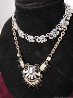 Both necklaces displayed on bust: silver choker on top, gold bib below