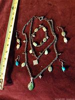 All six jewelry pieces laid out beside ruler for scale