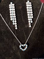 Full view of necklace and earrings on display stand