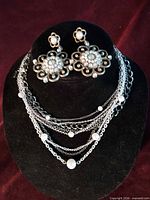 Full view of necklace draped on display bust with earrings placed above, showing overall design and components