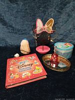 Group shot showcasing all items: book, salt lamp, Minnie holder with bracelets, perfume bottle on vanity tray, Little Mermaid music box