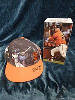 Front view of Buster Posey signed Giants cap next to boxed Joc Pederson bobblehead