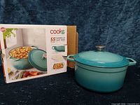 Dutch oven beside original box, exterior teal ombre finish visible