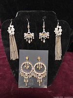 Overview of three pairs of vintage crystal earrings displayed on black stand