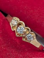Front view of gold ring with three heart-set diamonds