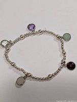 Full view of silver-tone beaded bracelet showing five gemstone charms