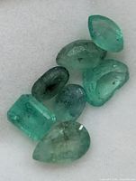 Close-up of seven loose emeralds showing shapes and clarity