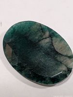 Top view of oval faceted emerald showing deep green color and inclusions
