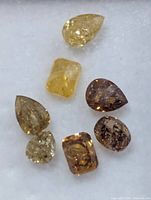 Close-up of seven loose diamonds showing colours and cuts