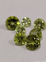 Seven round green peridot gemstones on white background