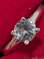 Close-up of round clear faceted stone within 4-prong silver setting