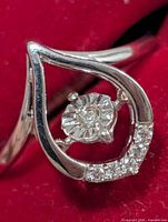 Front view showing teardrop frame, central dancing diamond, pave accent diamonds