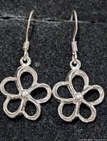 Front view of both silver flower earrings on dark background