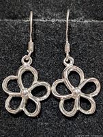 Front view of both silver flower earrings on black background