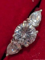 Top view of ring showing round center CZ and two pear side CZs in prong settings