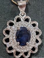 front view of pendant showing sapphire, CZ halo and scalloped frame