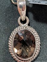 Front view of silver pendant showing oval smoky quartz and rope bezel
