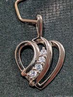 Front view of silver-tone heart pendant with four CZ stones