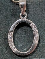 Front view of oval silver pendant with CZ bands