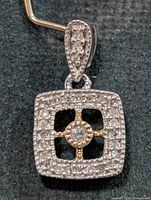 Front view of square sterling silver diamond pendant showing pave setting and yellow-tone central accent