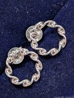 Front view of silver twisted circle earrings on fabric