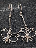 Front view of both silver butterfly earrings showing design and hooks