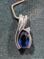Front view of pendant showing blue stone, silver frame and bail