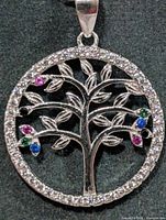 Front view of round silver tree of life pendant with stones