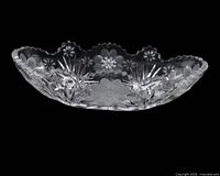 Top view of cut glass oval bowl showing daisy pattern and scalloped rim