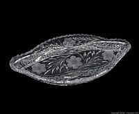 Full view of the oval cut glass tray showing floral intaglio and scalloped rim