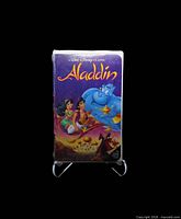 Front of sealed Aladdin Black Diamond VHS in clamshell case on stand