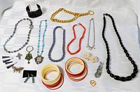 Overall view of assorted necklaces, bangles, cuff bracelet, earrings, pendants and brooch on white background