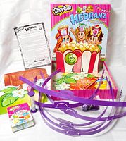 Full contents laid out: box lid, instruction sheet, cards, cardboard pieces, purple headbands, timer