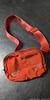 Front view of bright orange Aperol Spritz waist bag showing logo, graphics, strap and zipper