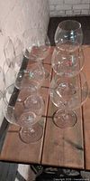 Six clear balloon goblets arranged on wooden surface