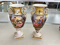 Front view showing both vases with painted panels and gilded handles