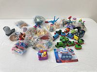 Group shot showing all plastic toys, including mini trains, sealed Spider-Man pack, Simpsons figure and multiple bagged items
