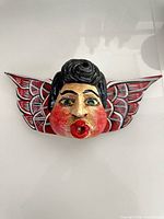 Front view of carved wooden winged face decor