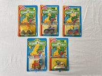 Group shot of five sealed Sesame Street die-cast vehicles on cards