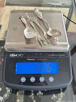 Four sterling silver utensils on scale reading 87.6 g