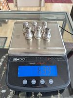 All six sterling silver salt shakers on scale displaying 63.9 g