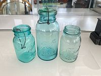 Three aqua glass jars standing side by side