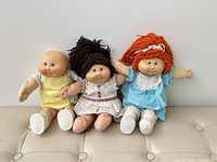 Front view of three Cabbage Patch Kids dolls seated side by side