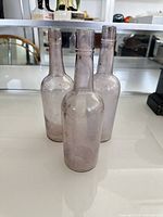 Front view of three purple glass bottles