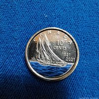 Reverse of colorized 1921-2021 Canadian 10-cent coin on blue fabric