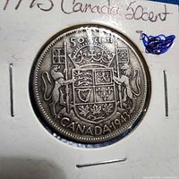 Reverse of 1943 Canadian 50 cent coin in flip, coat of arms visible