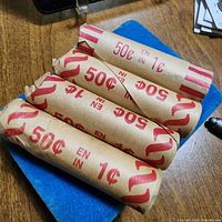 Four rolls of pennies on table, wrappers marked 50¢