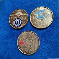 Overview of all three coloured Canadian dollar coins on blue fabric